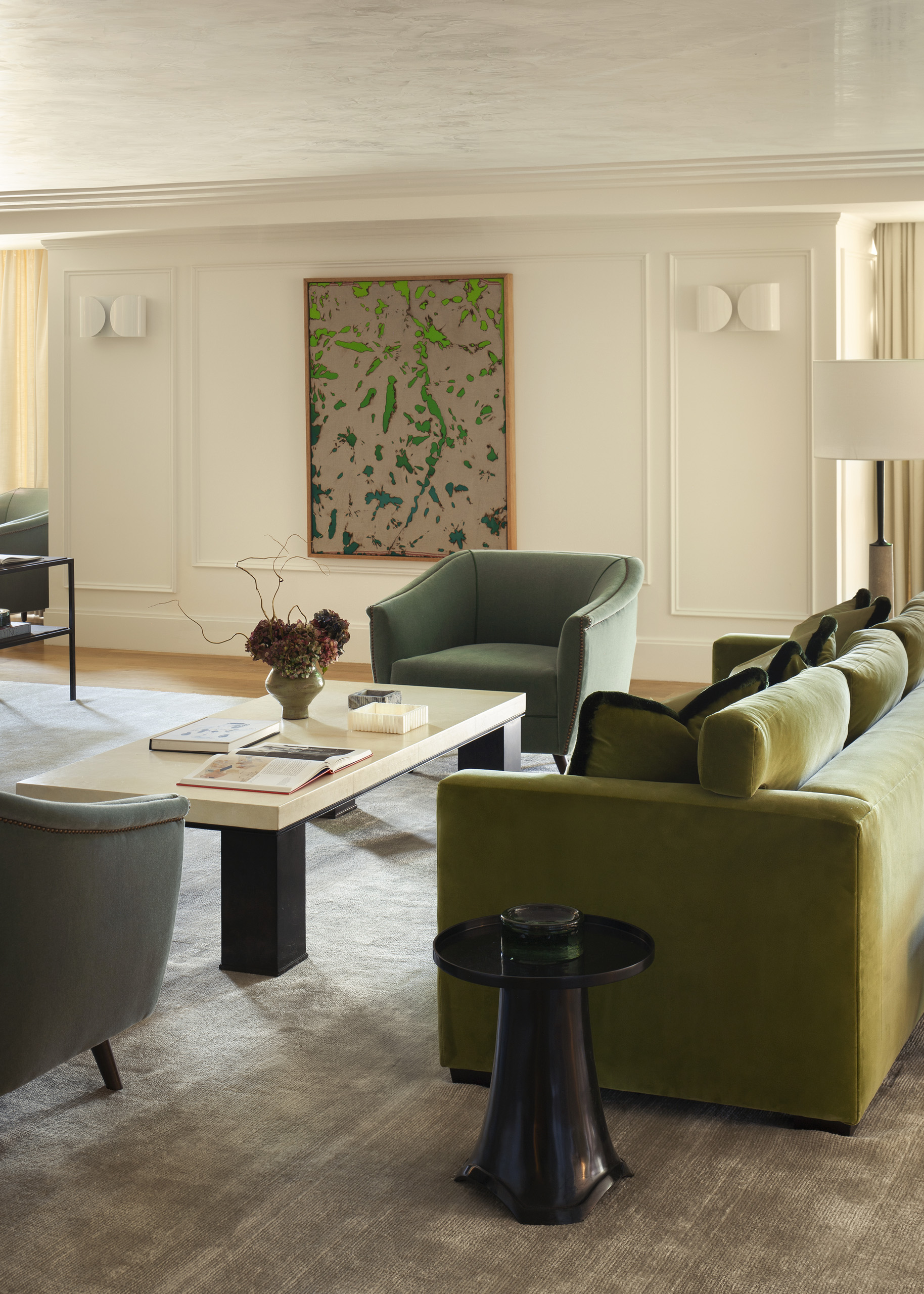 Sunlit lounge with green sofa and modern artwork.