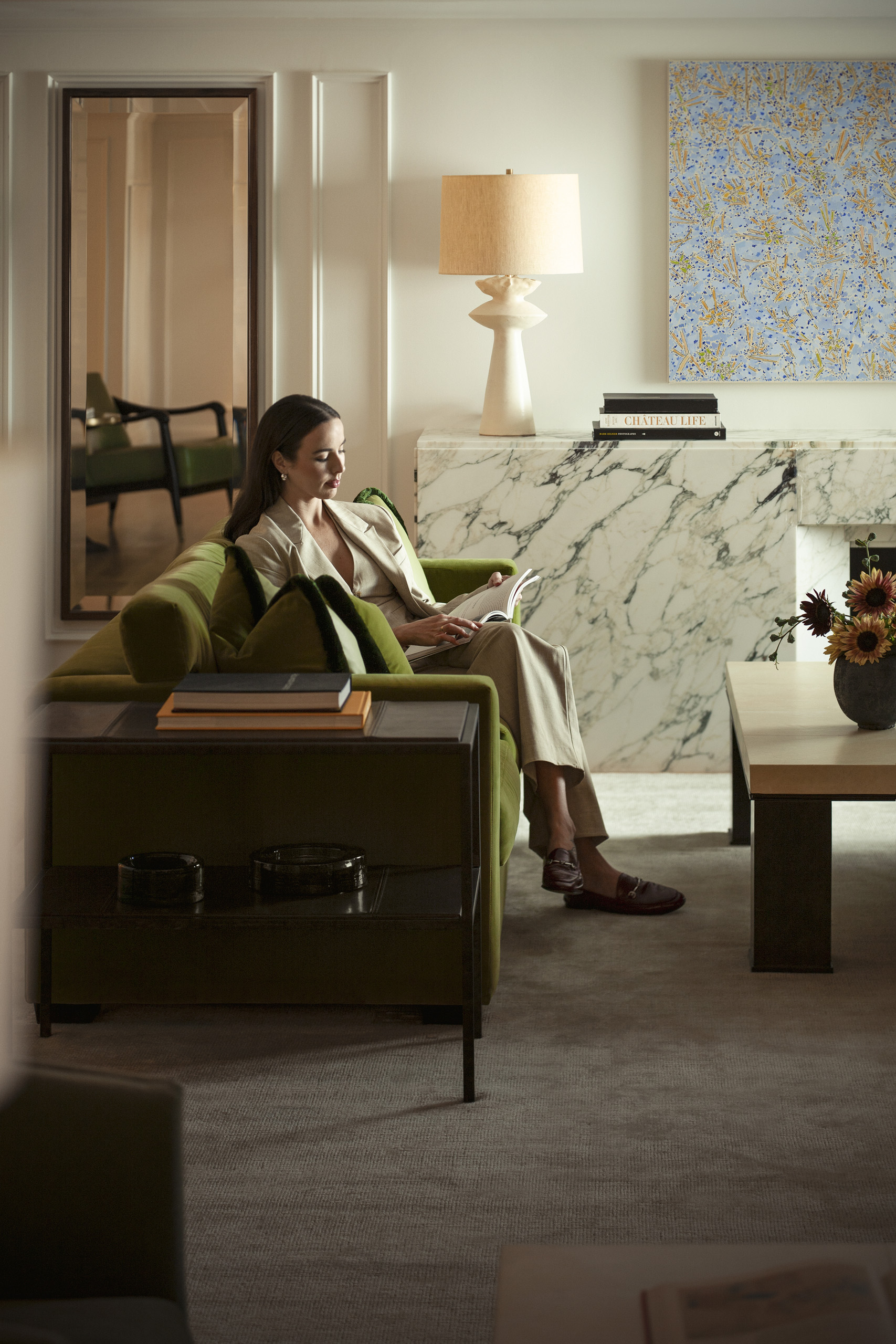 Woman reading on green sofa in quiet lounge.