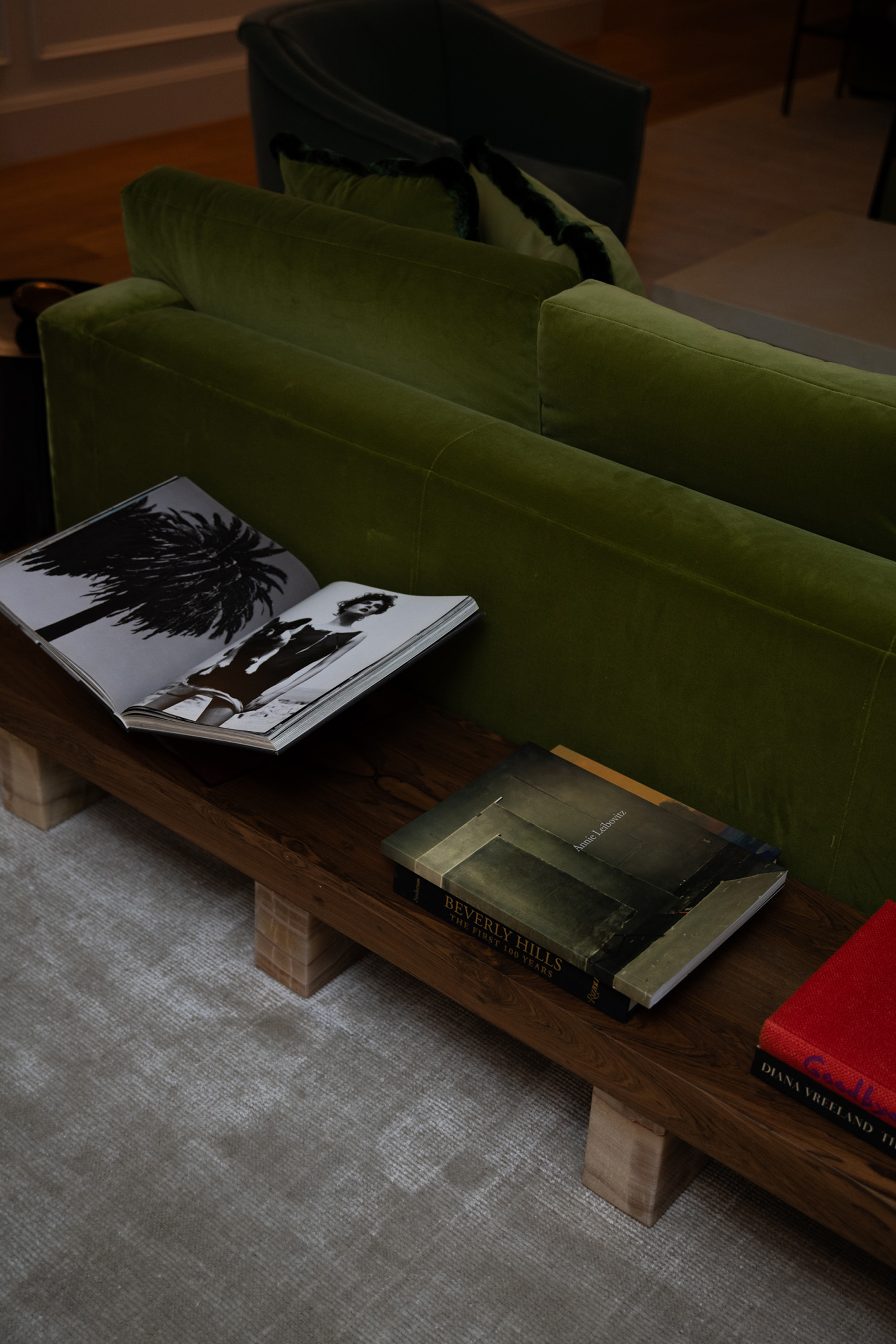 Coffee table books beside green sofa and chairs.