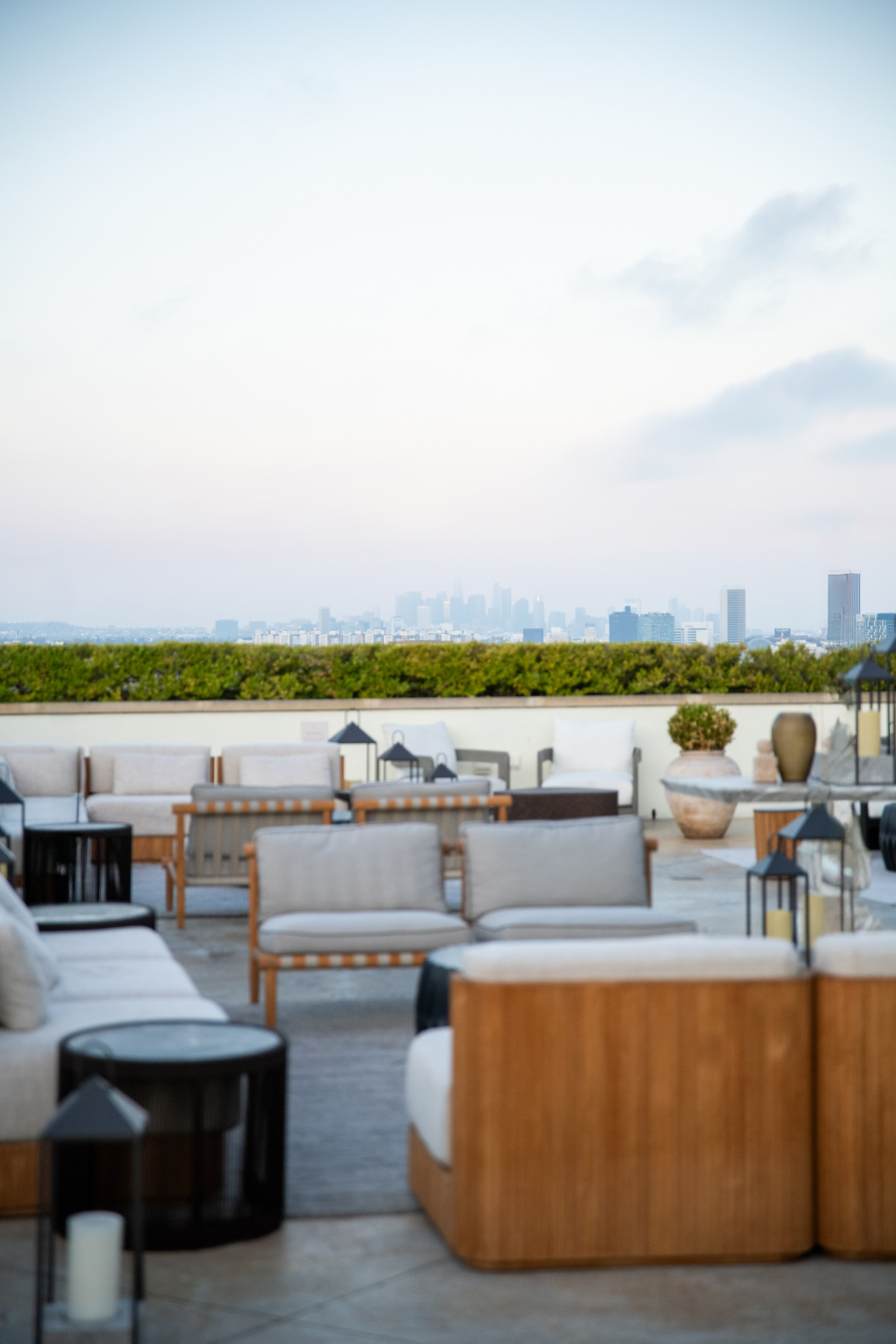 Rooftop seating area with cushioned sofas and a city skyline in the distance.