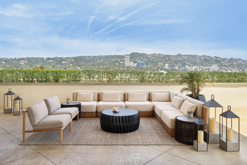 Outdoor sectional seating arrangement on a rooftop terrace overlooking hills on a sunny day.