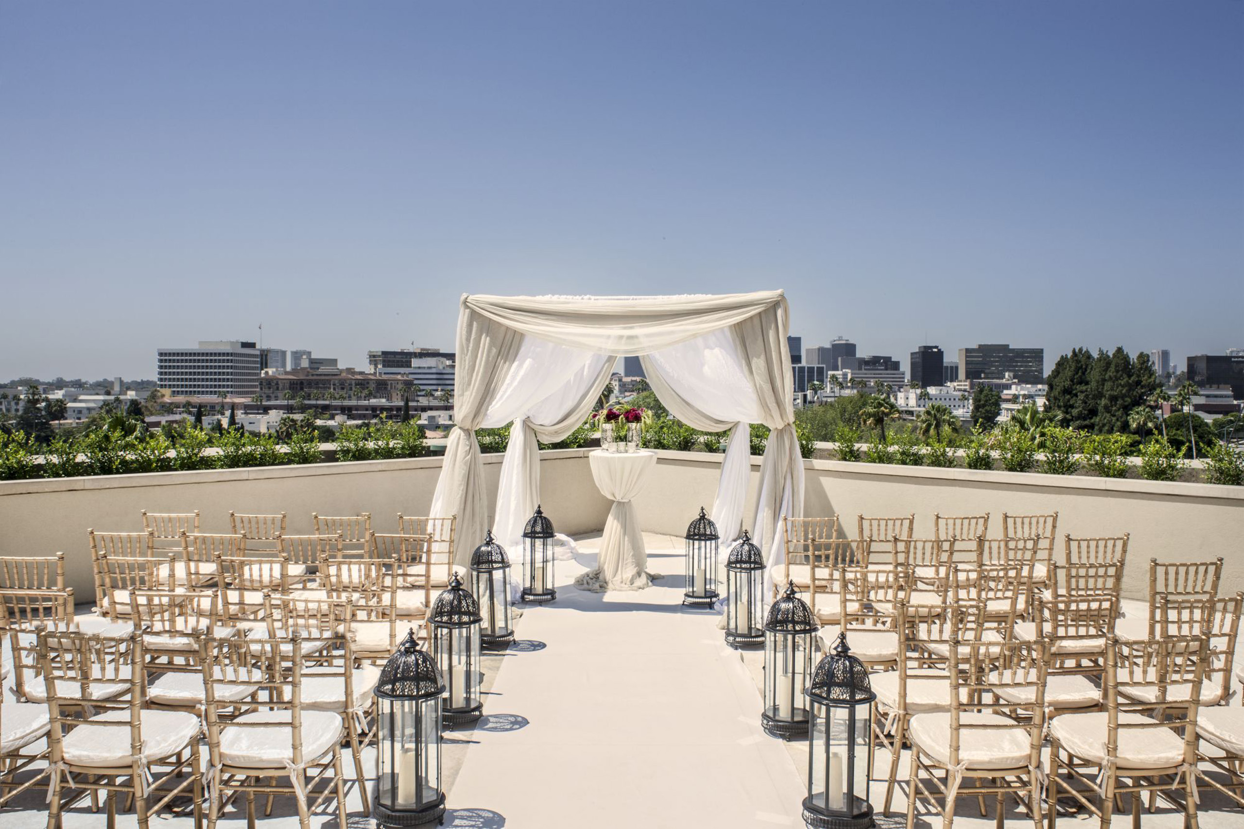 Rooftop wedding ceremony setup with white draped canopy and rows of chairs facing the skyline.