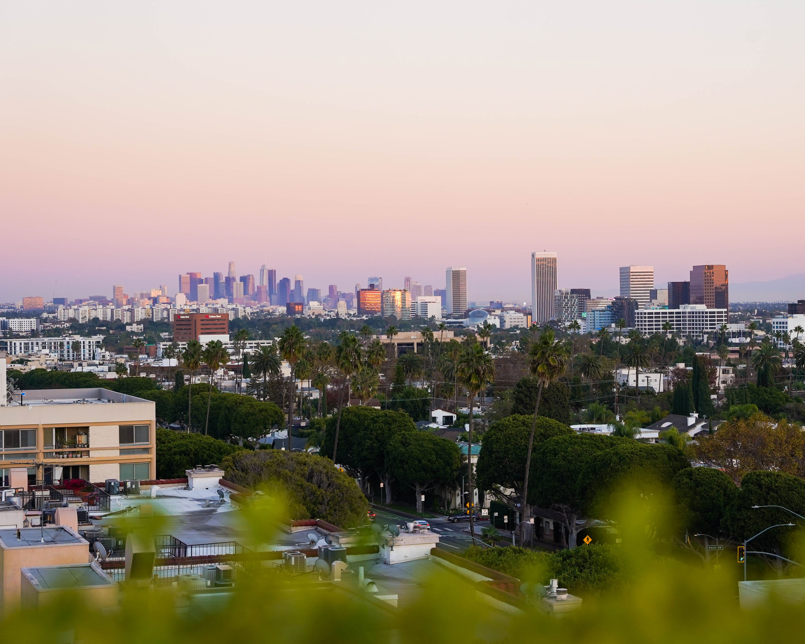 Wide rooftop terrace with multiple seating areas, lantern decor, and hills in the background.