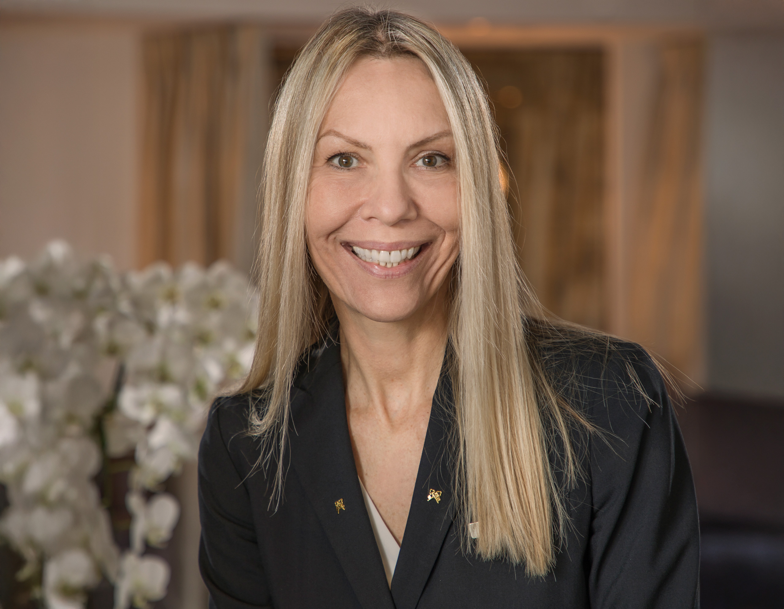 Smiling concierge in blazer, warmly lit hotel background.