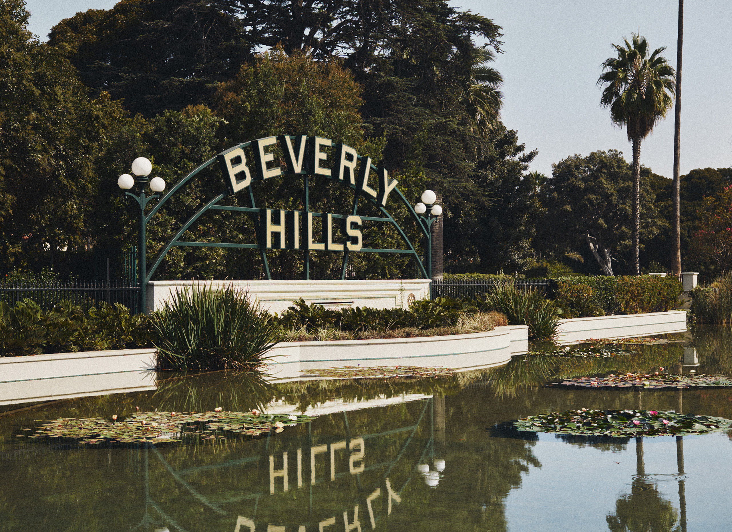 Beverly Hills sign reflected in pond with lily pads.