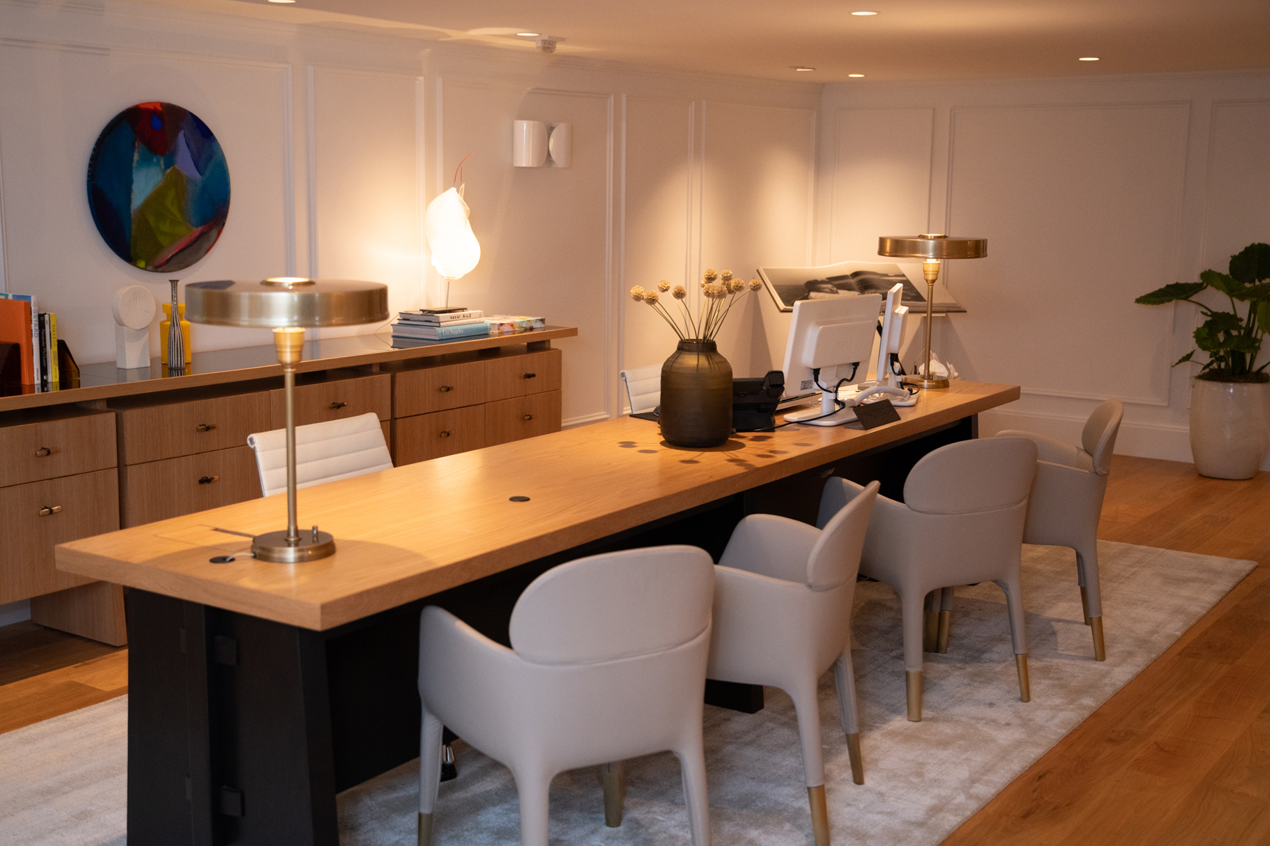 Modern concierge desk with chairs, lamps, and artwork.