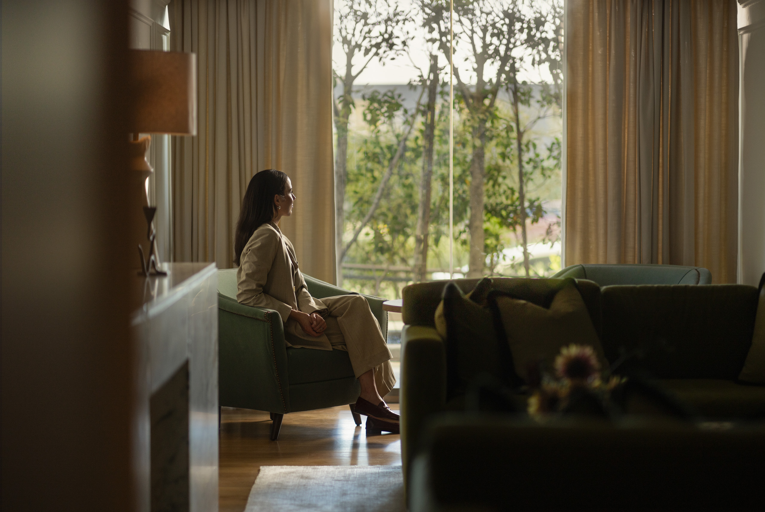 Woman seated by window in elegant hotel lounge.