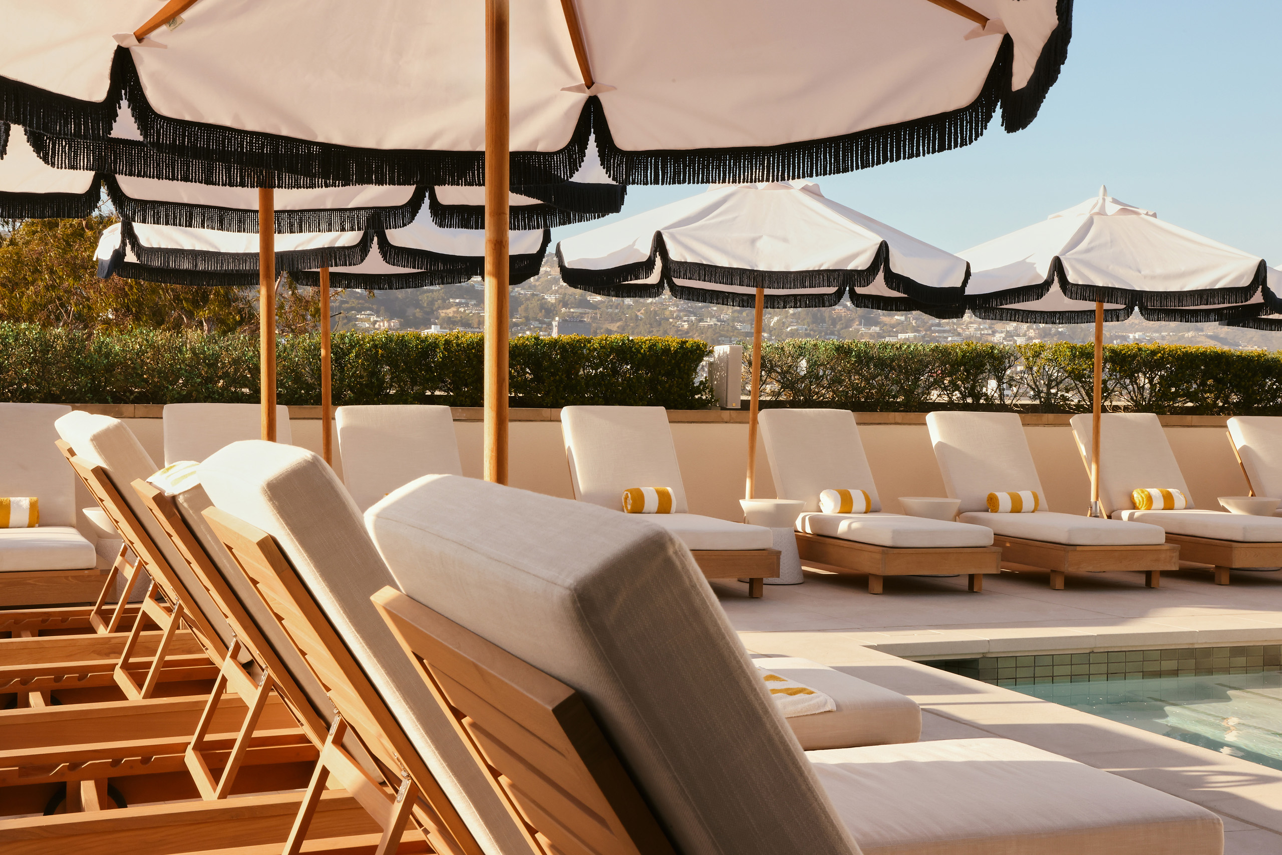 Poolside loungers beneath striped umbrellas in sunlight