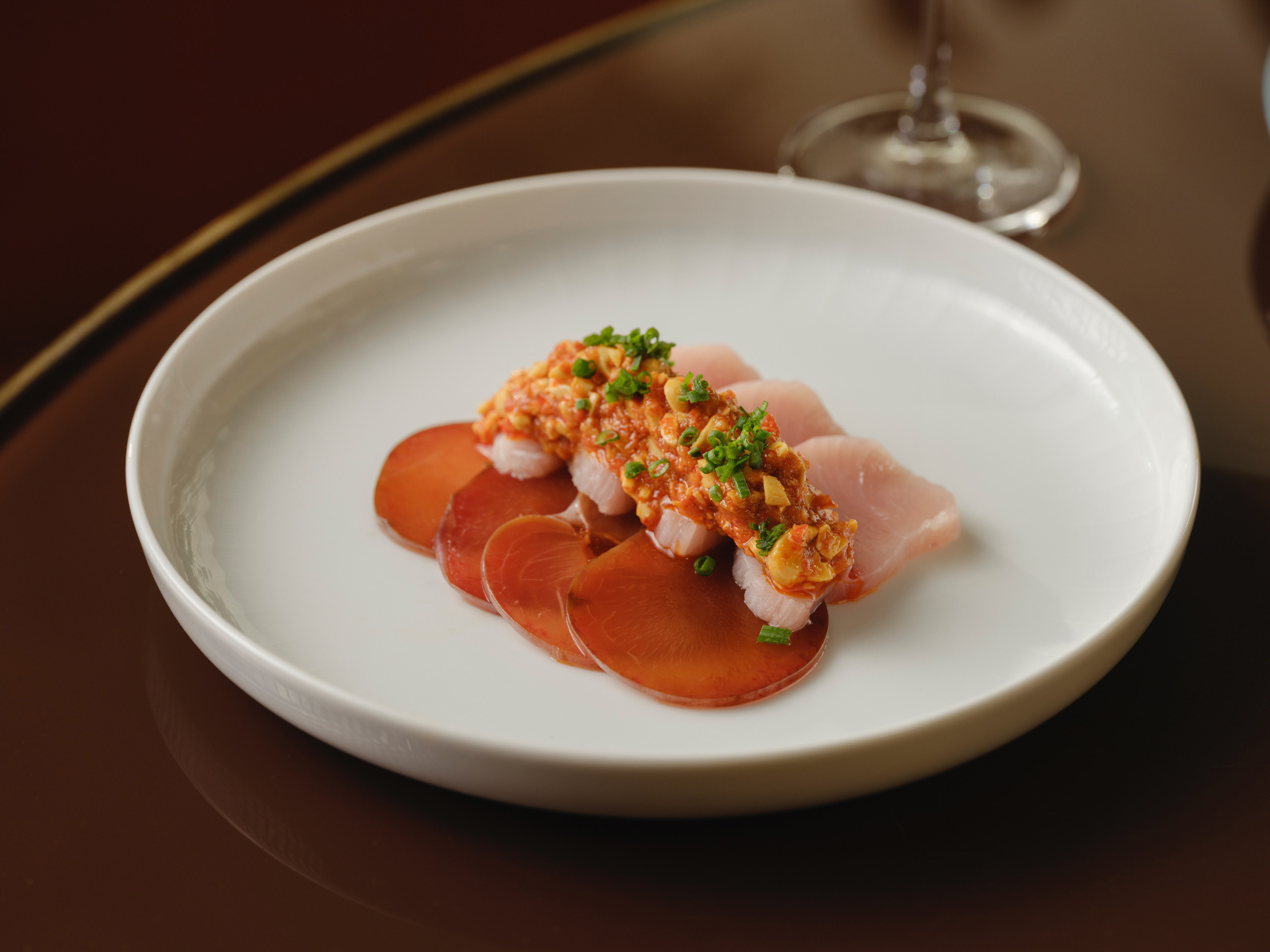 Plated crudo with chili topping on white dish