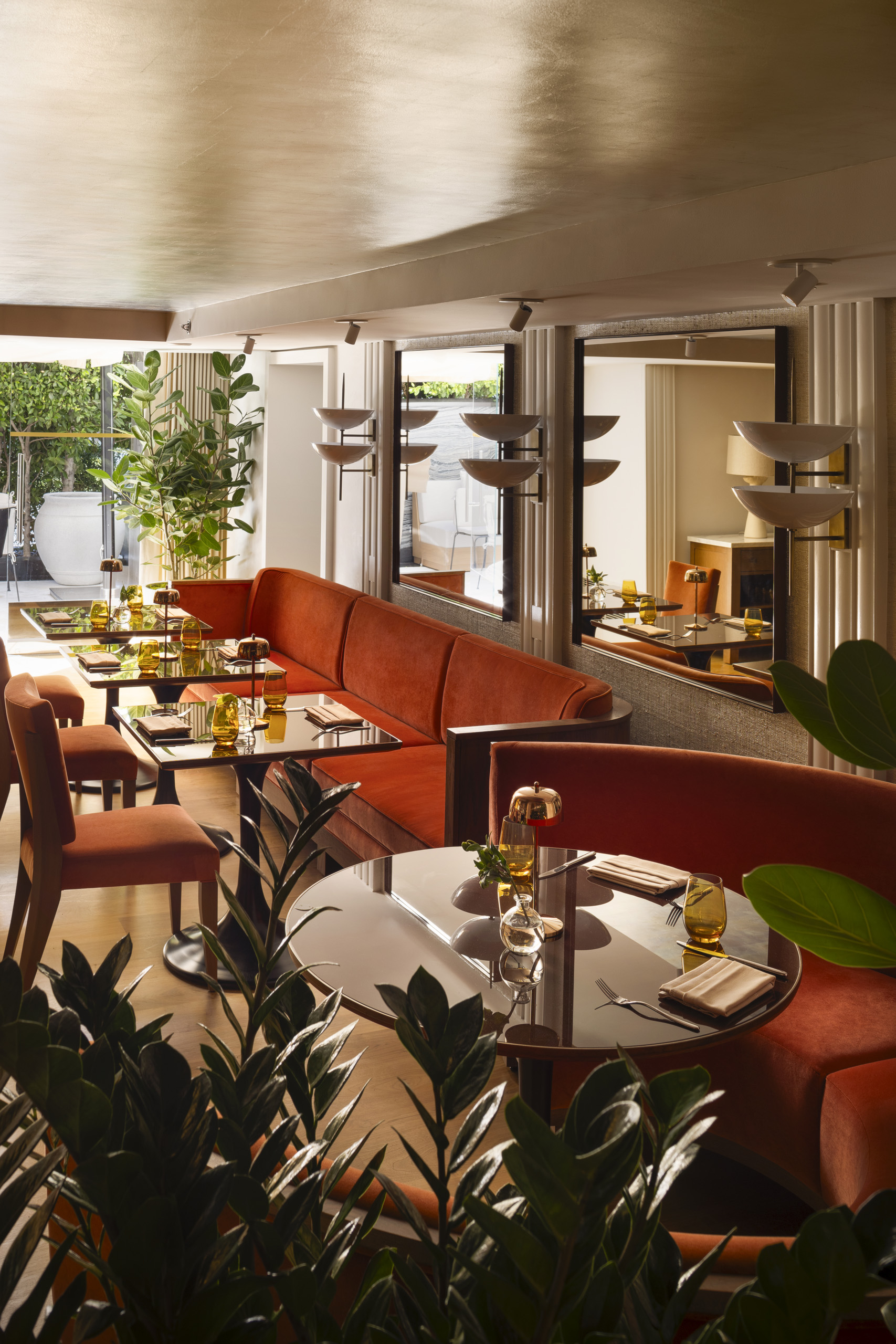 Sunlit restaurant booths with mirrors and plants