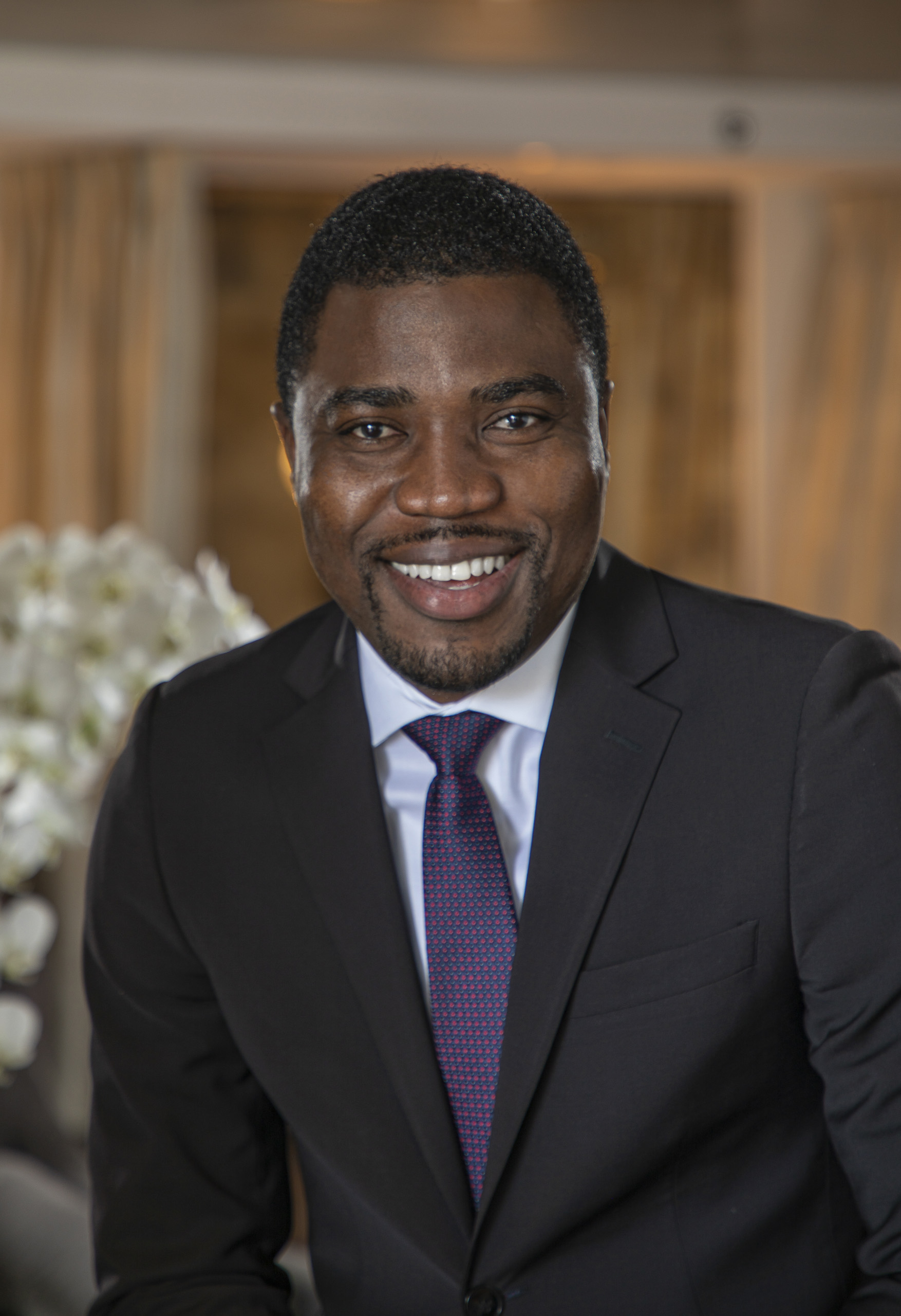Smiling man in suit and tie, hotel lobby background.