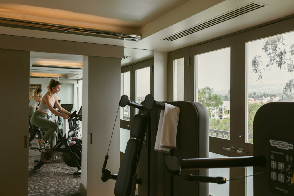 Woman cycling in gym, equipment by windows