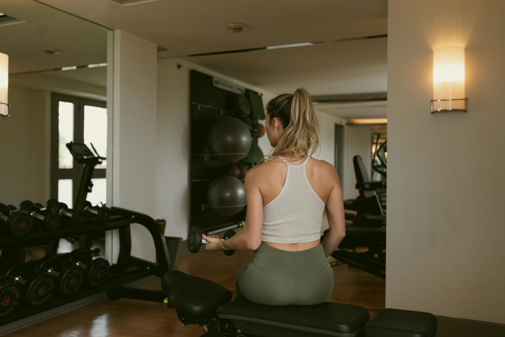Woman lifting weights on bench, gym behind