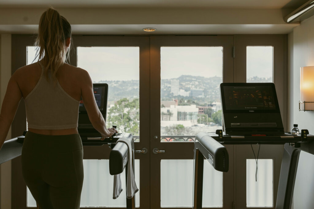 Woman on treadmill facing windows and skyline