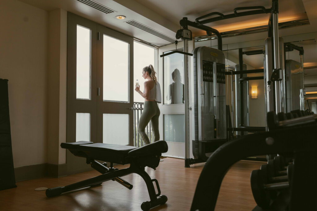 Woman holding water bottle beside gym windows