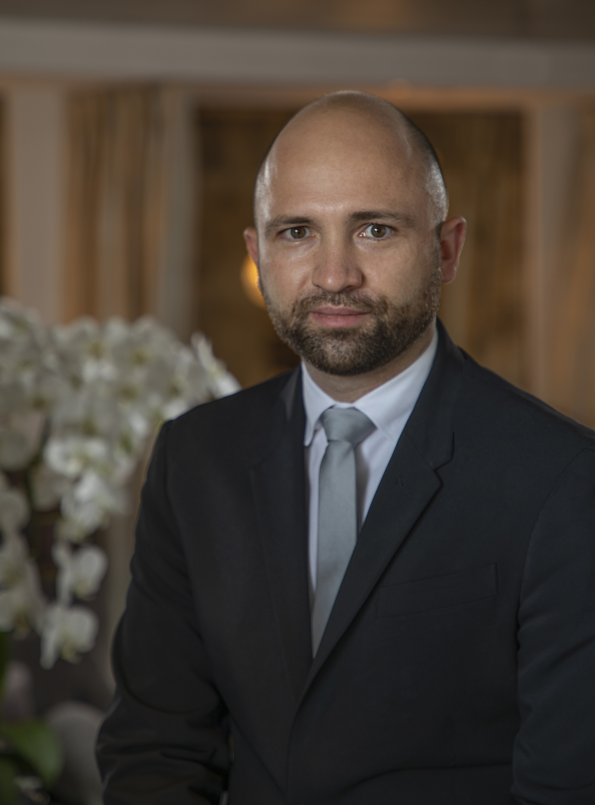 Bald man in suit and tie, hotel lobby background.