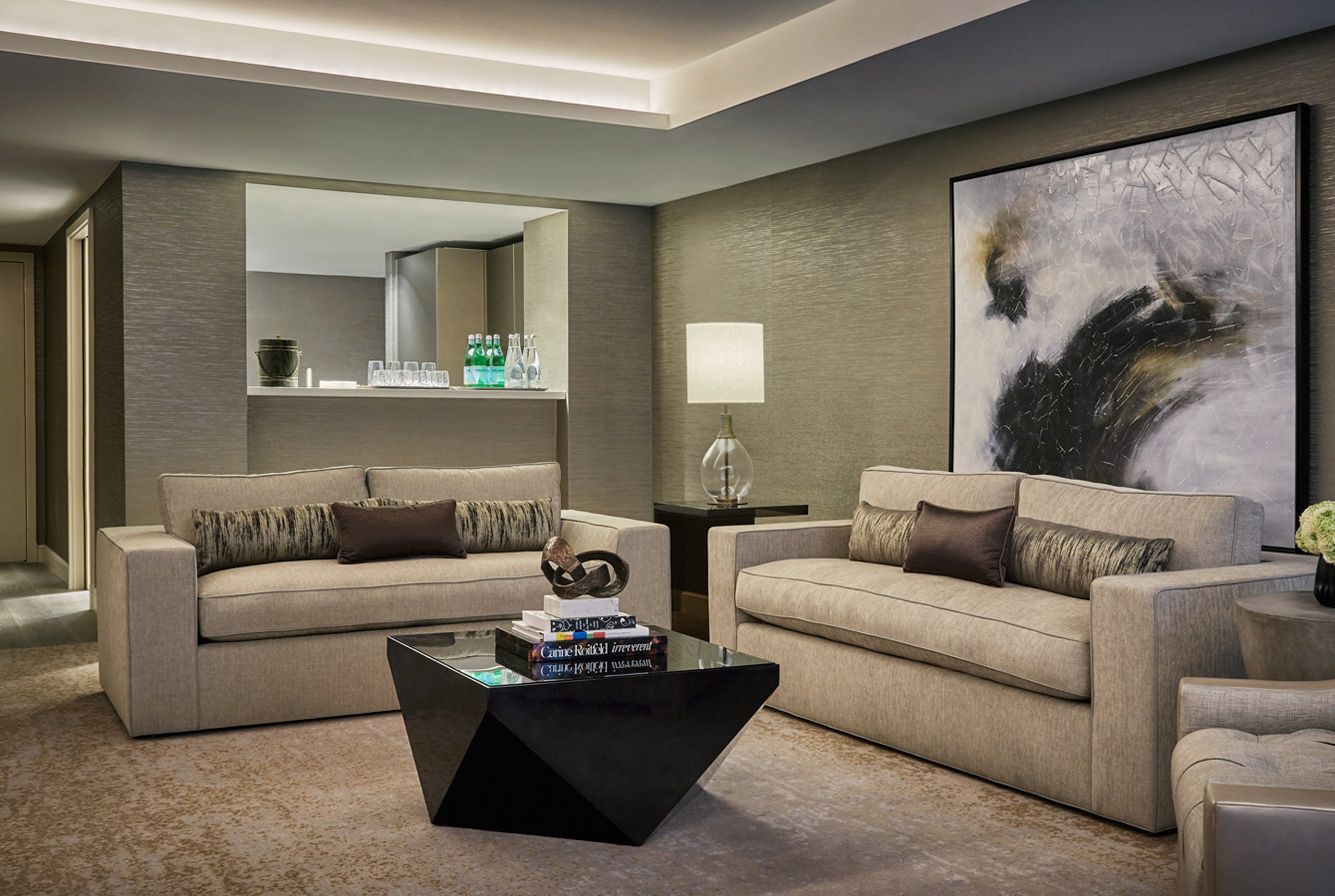 Suite lounge with sofas, bar nook, lamp, and abstract art.