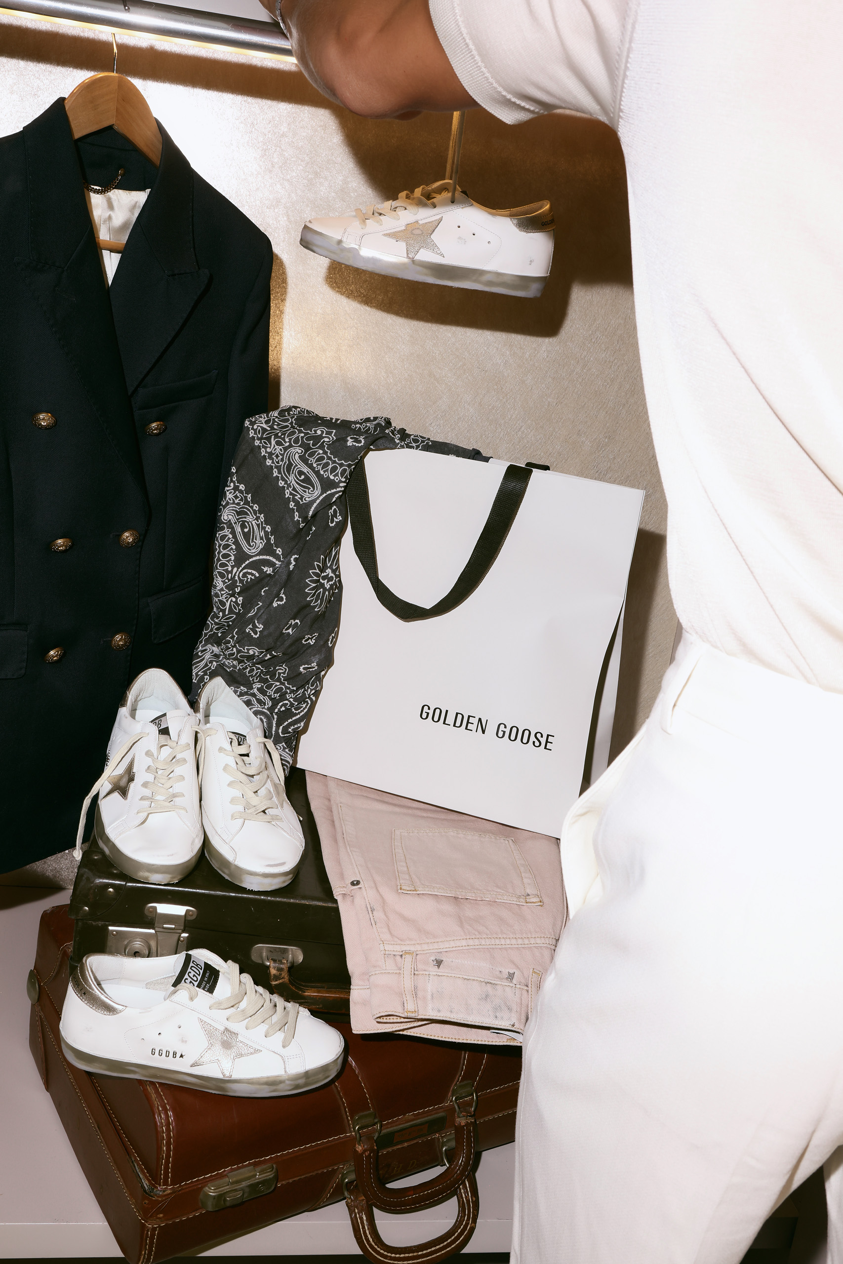 Golden Goose sneakers and bag arranged on stacked luggage