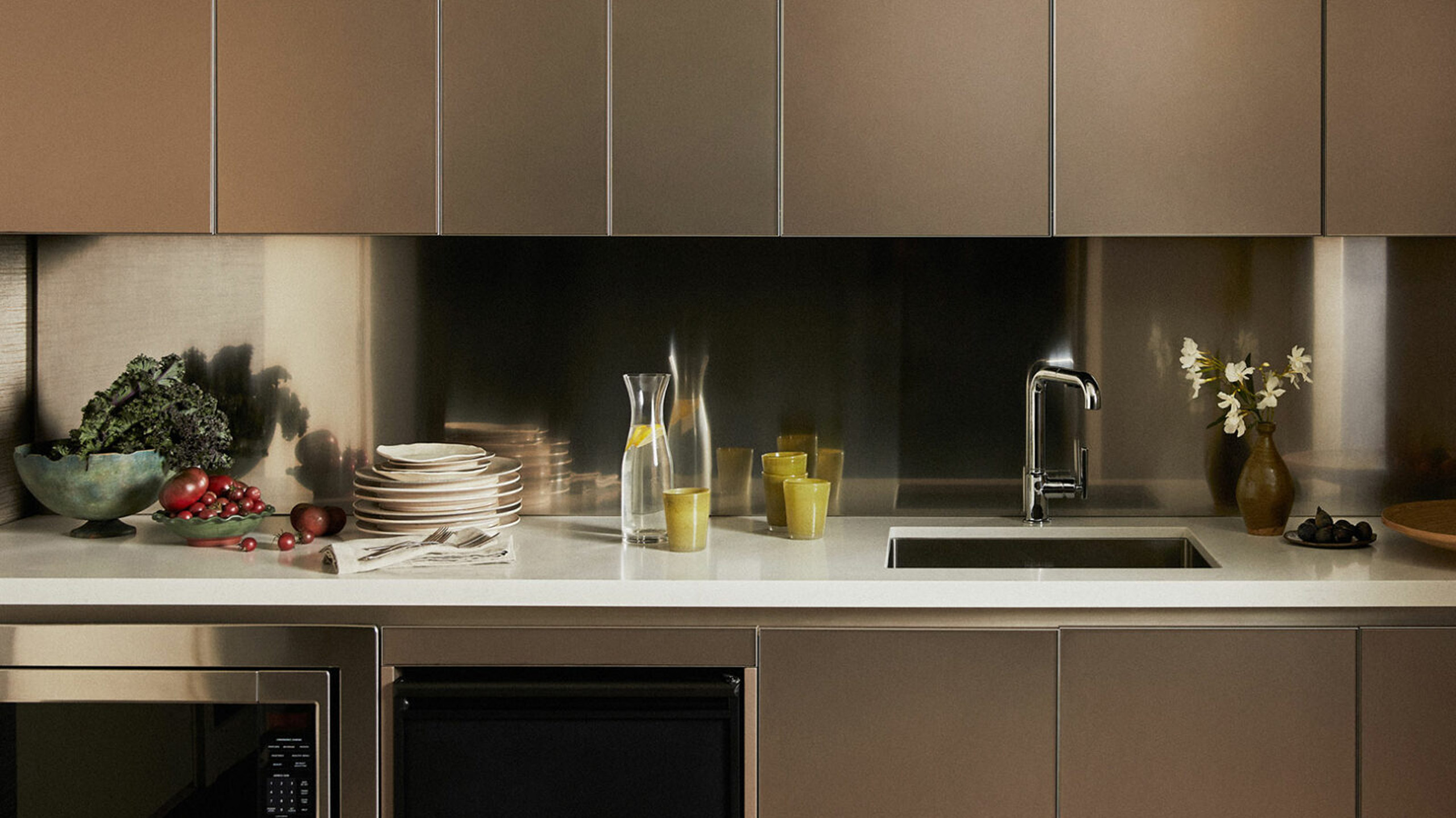 Modern kitchenette with sink, dishes, and fresh produce