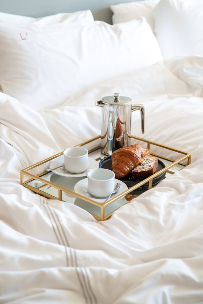 Breakfast tray with coffee and pastries on bed