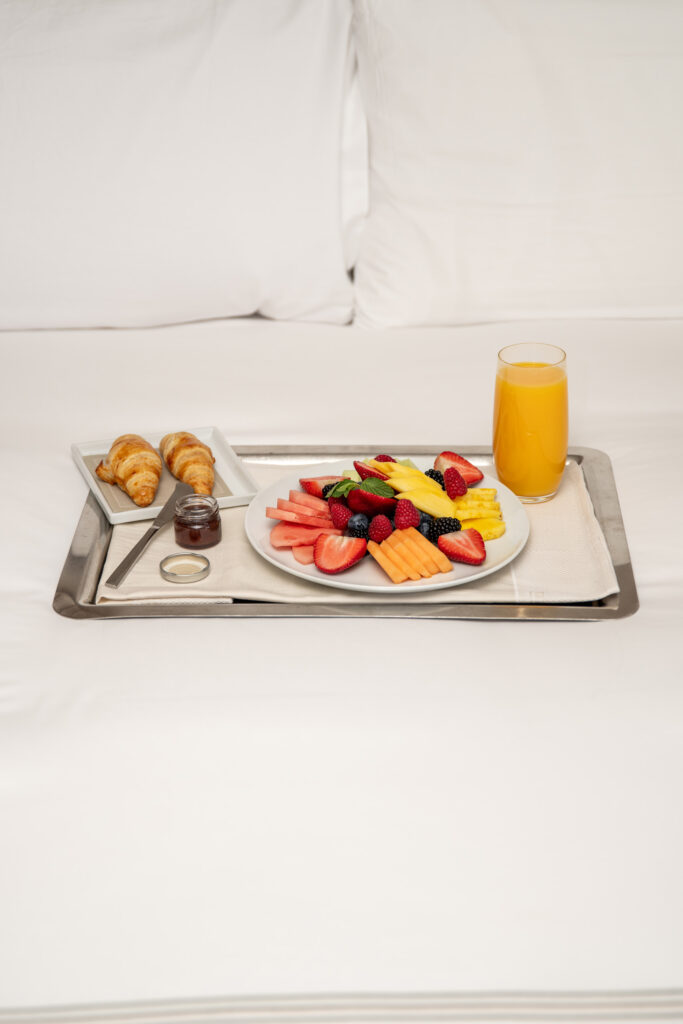 Fruit and croissants with orange juice on tray
