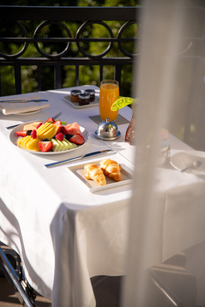 Outdoor breakfast table with fruit, croissants, and juice