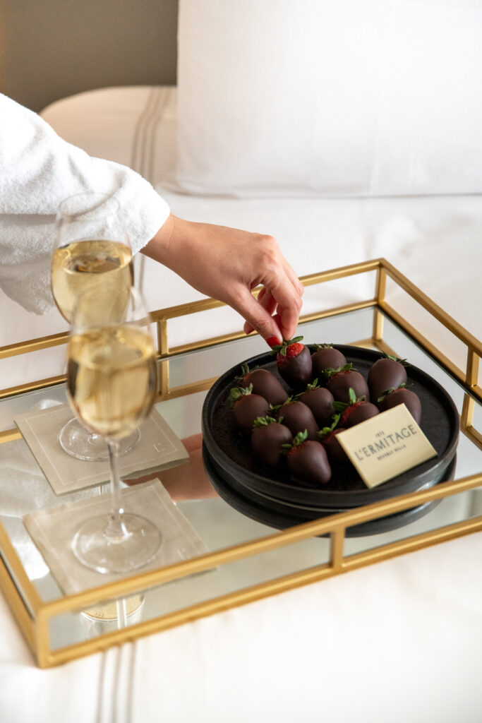 Hand reaching for chocolate-covered strawberries with champagne