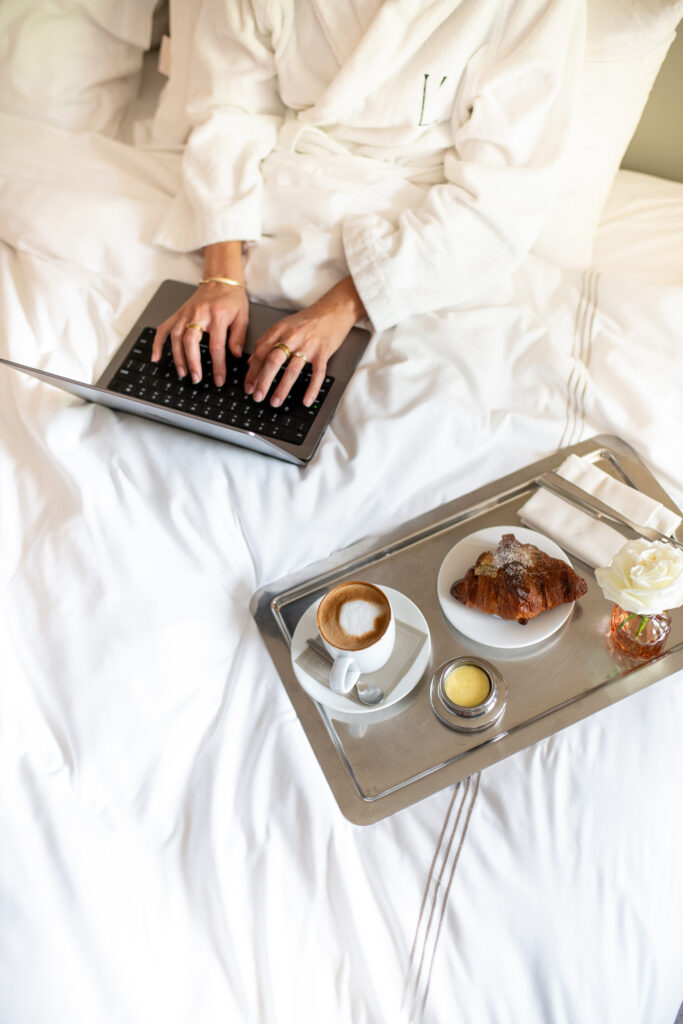 Guest in robe working beside breakfast tray