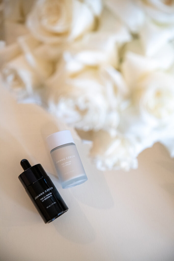 Two skincare bottles on white surface with soft flowers