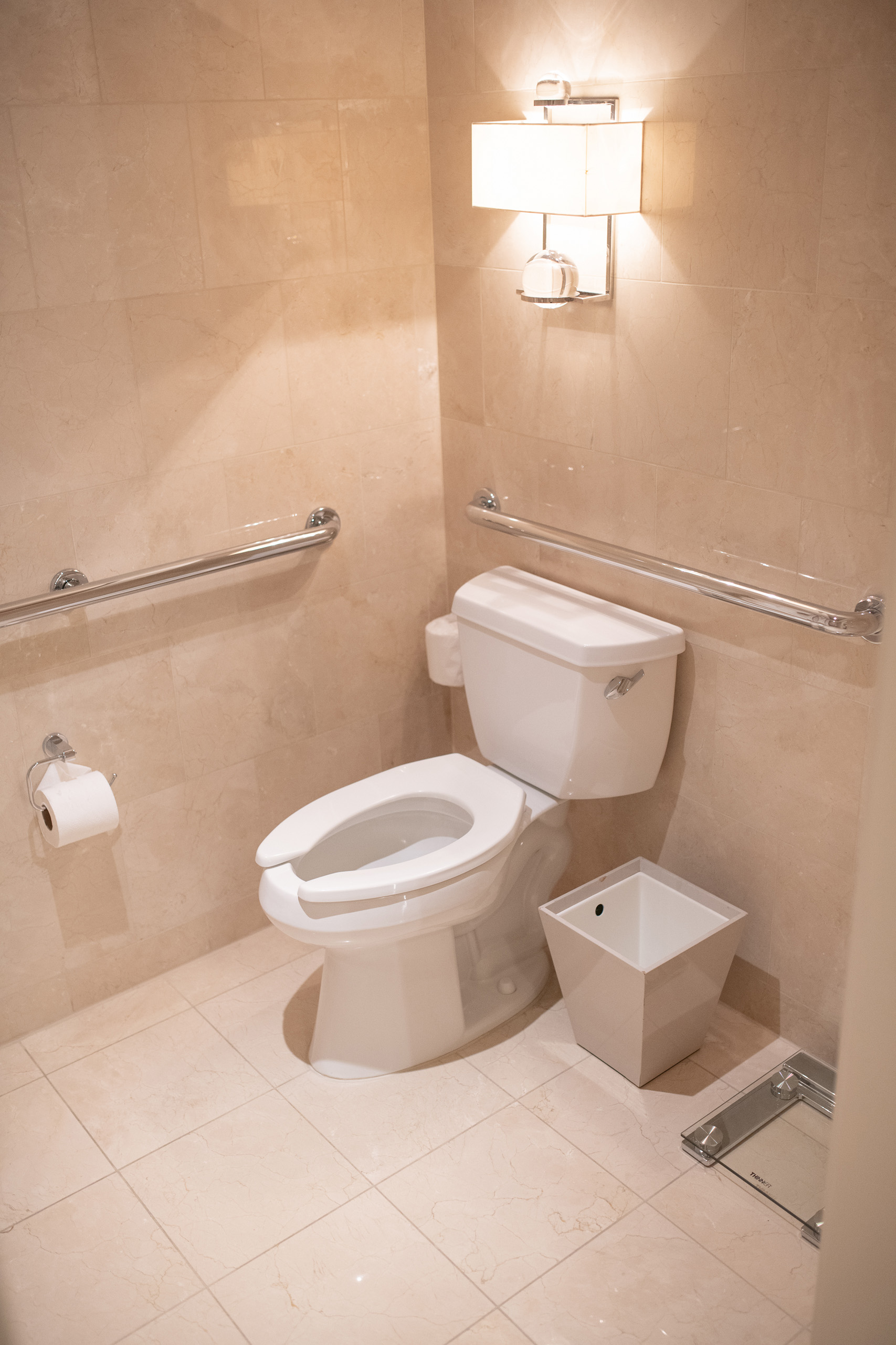 Accessible toilet with grab bars and wall sconce lighting
