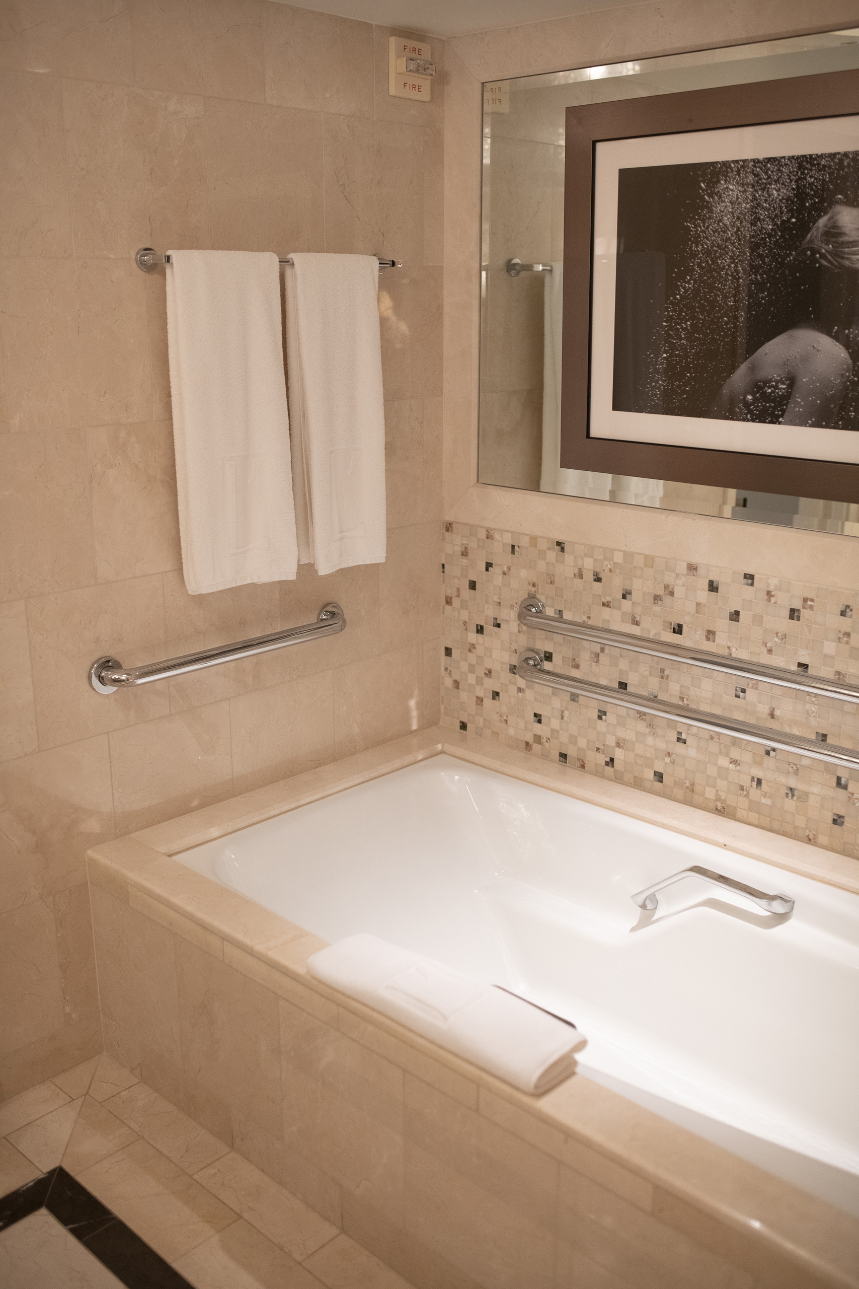 Accessible bathtub with towels on rack and mosaic tile accent