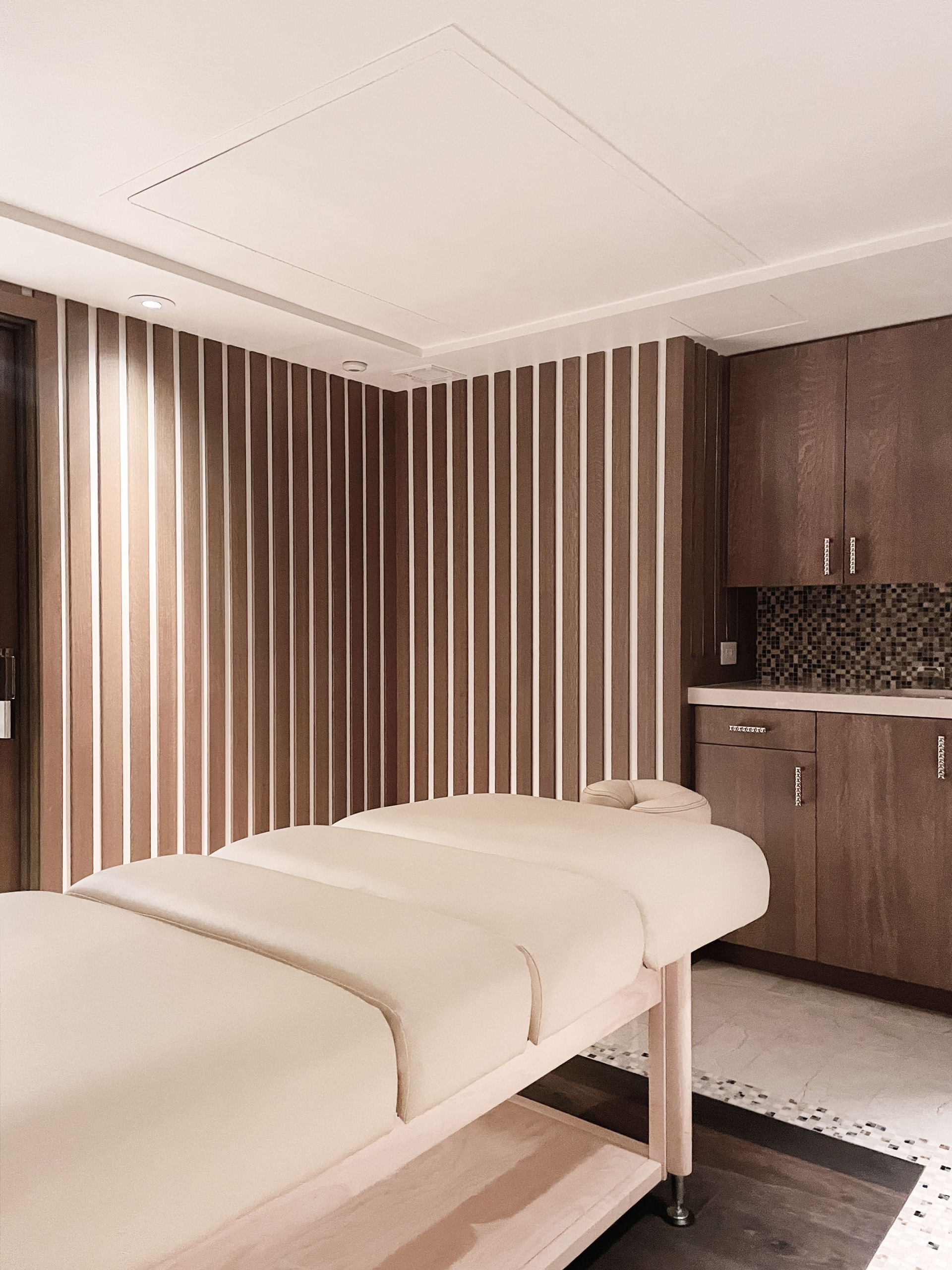 Spa room with massage table and wood slat wall.