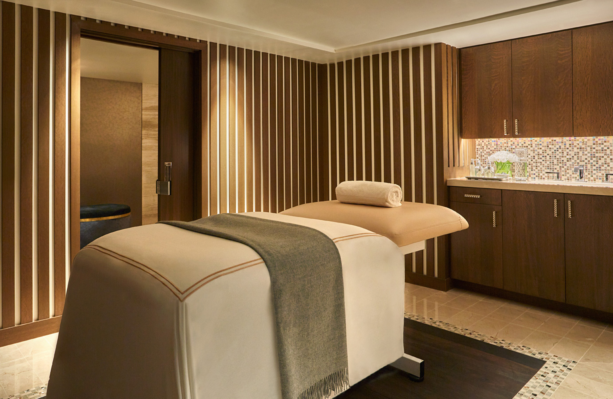 Massage table in warm spa room with cabinetry.