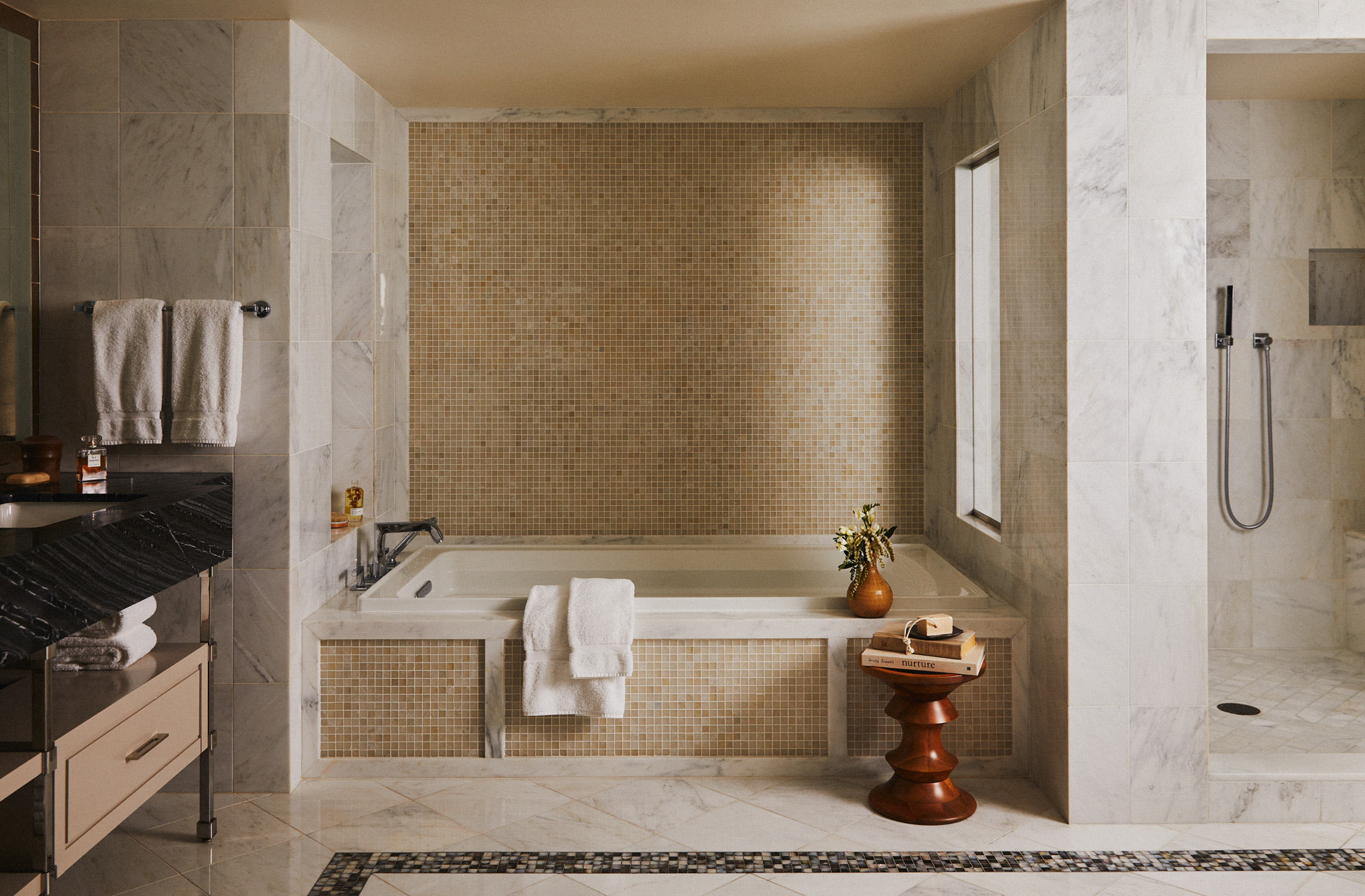 Marble soaking tub with mosaic wall and walk-in shower.