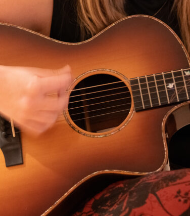 Close-up of hands strumming acoustic guitar.