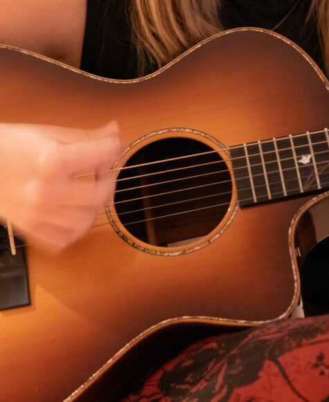 Close-up of hands strumming acoustic guitar.
