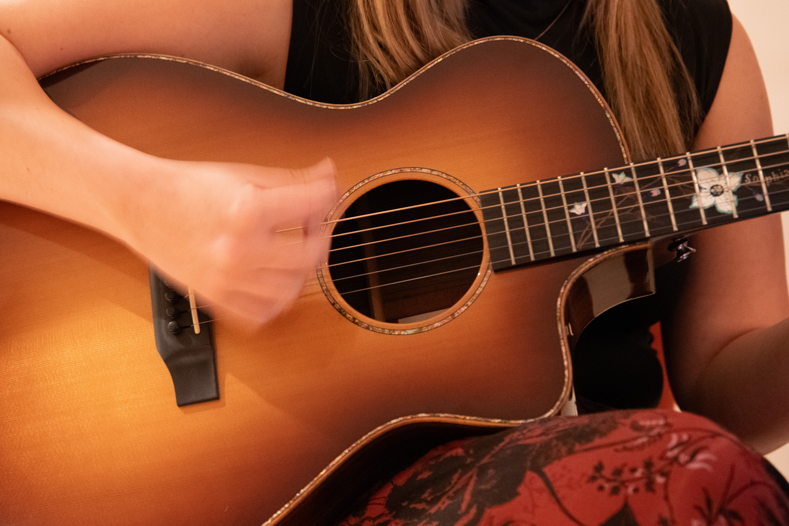 Close-up of hands strumming acoustic guitar.