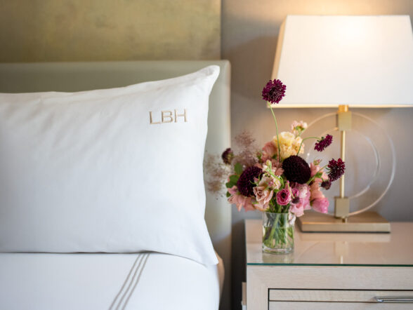 Monogrammed pillow beside lamp and fresh flower bouquet