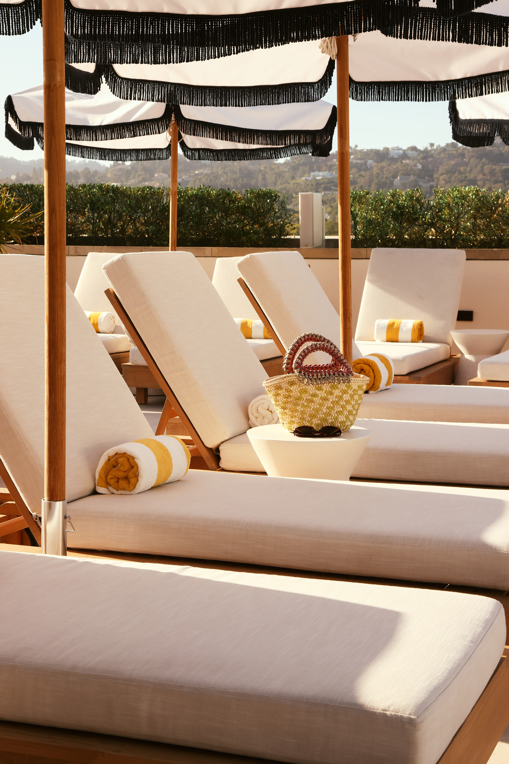 Close-up of pool loungers with striped towels under shaded umbrellas
