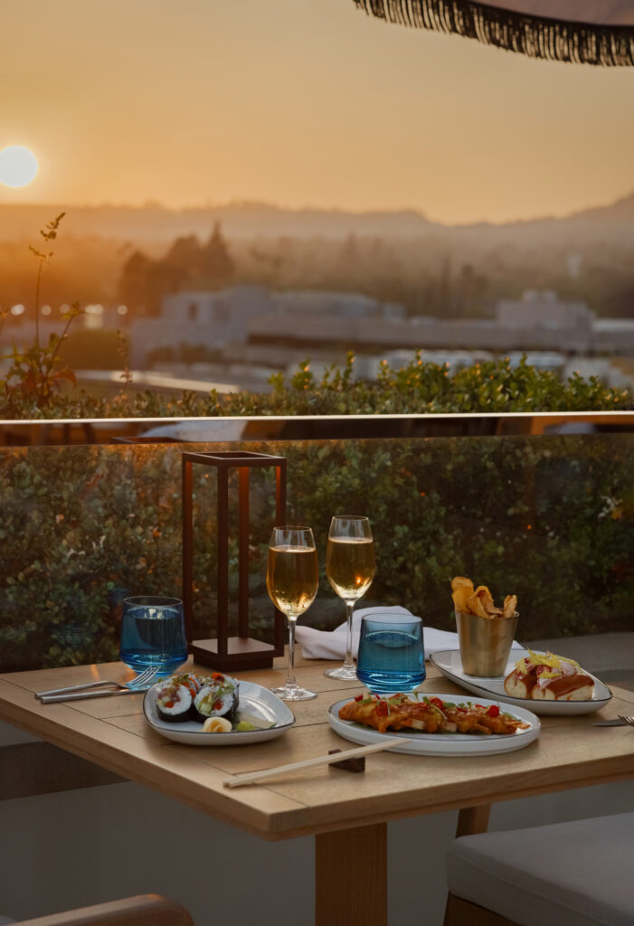 Sunset rooftop dining table with sushi and champagne