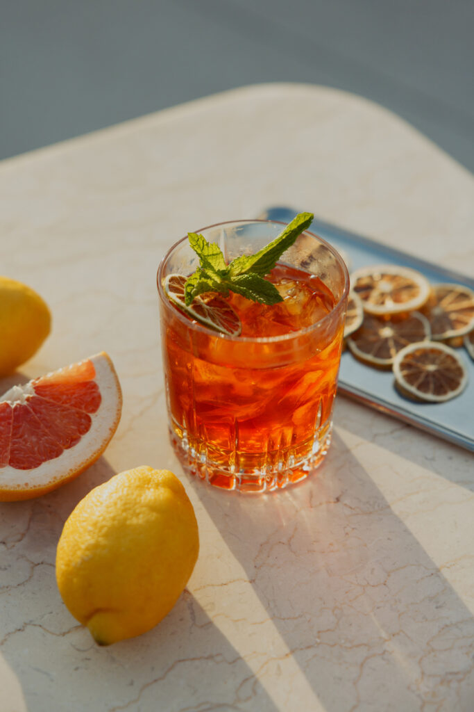 Orange cocktail with mint beside sliced citrus