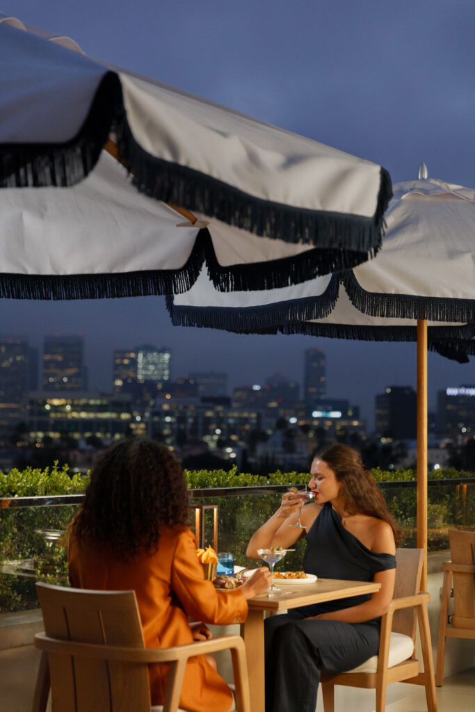 Two women dining on rooftop at night.