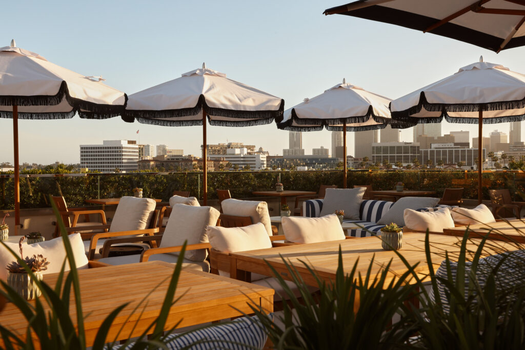 Rooftop dining under umbrellas with skyline backdrop.