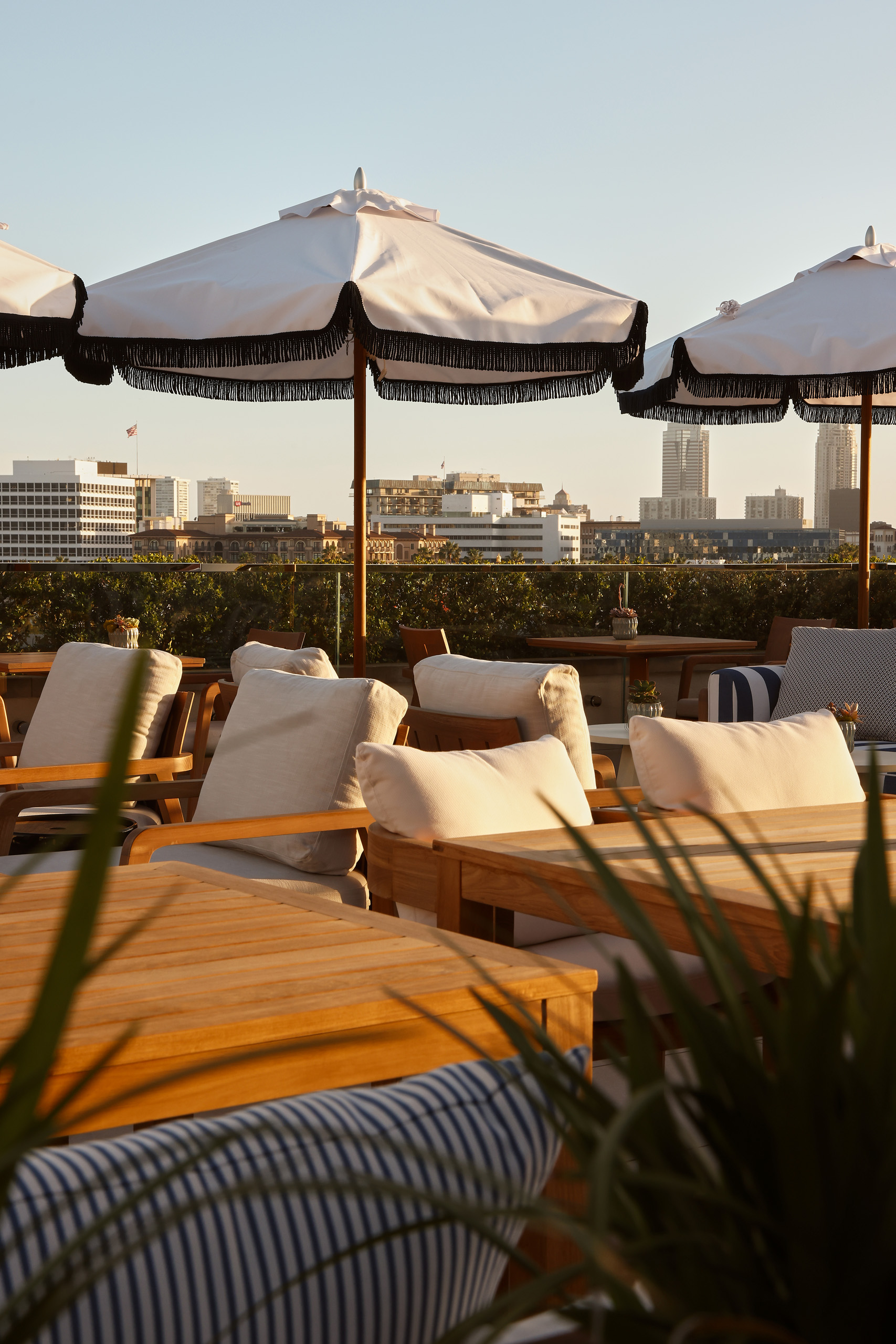 Rooftop seating beneath umbrellas with warm evening light and city views