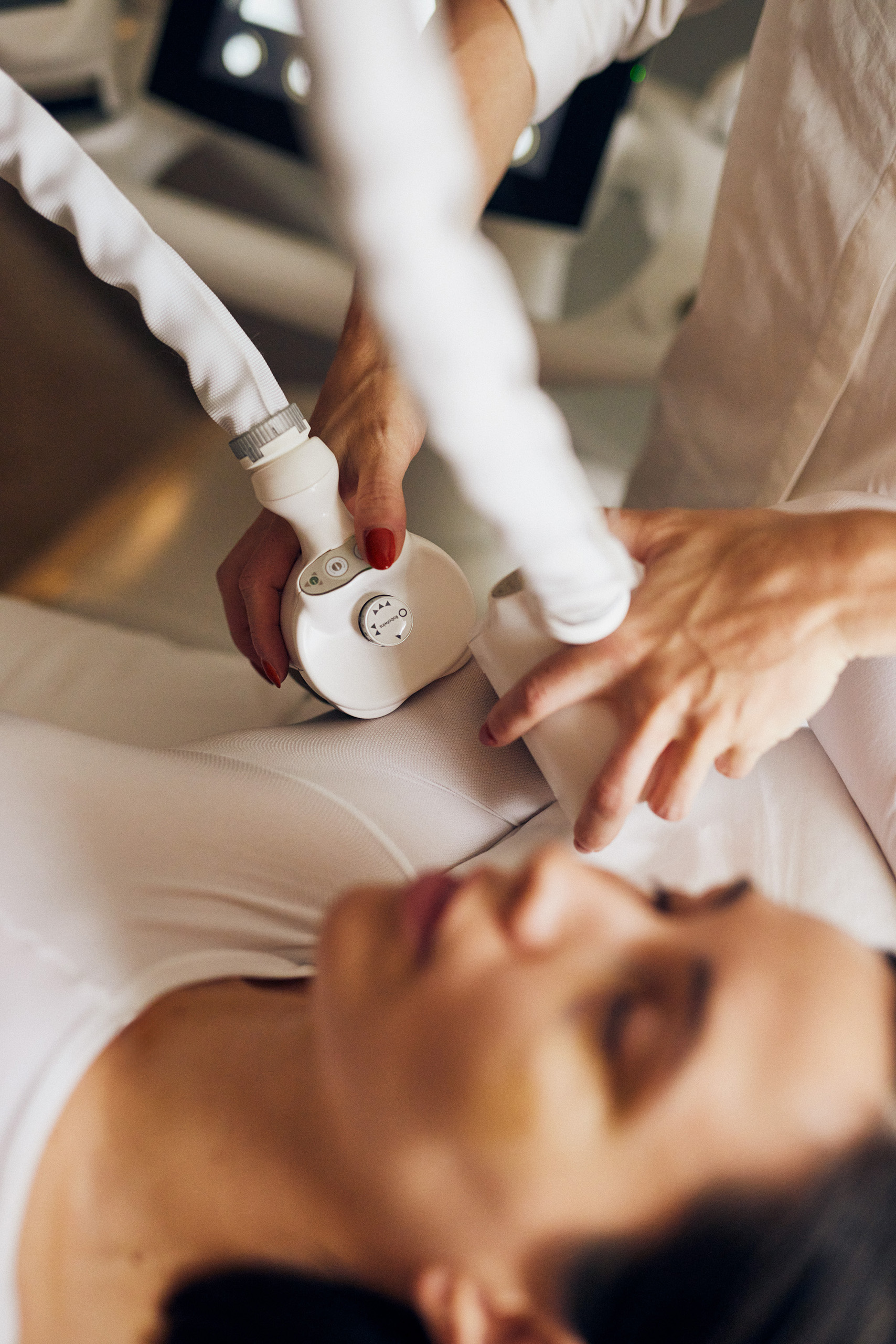 Body contouring treatment on woman lying on bed.