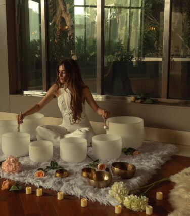 Woman plays crystal bowls during rooftop sound bath.