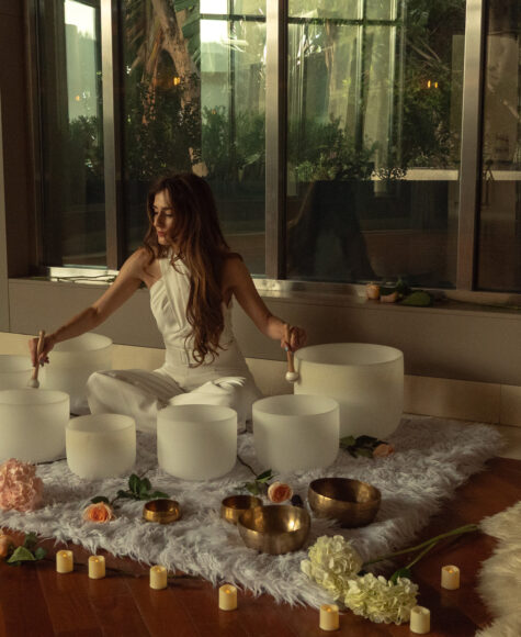 Woman plays crystal bowls during rooftop sound bath.