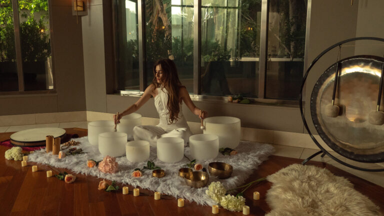 Woman plays crystal bowls during rooftop sound bath.
