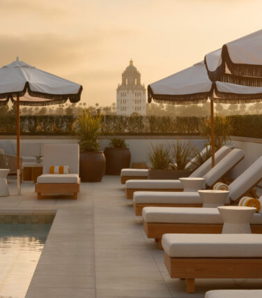 Rooftop pool loungers and umbrellas at golden sunset.