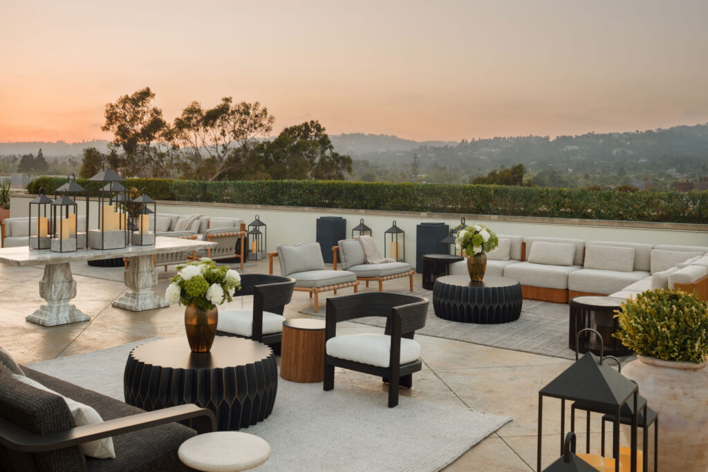 Panoramic rooftop terrace with lounge seating, lanterns, and hillside views at sunset